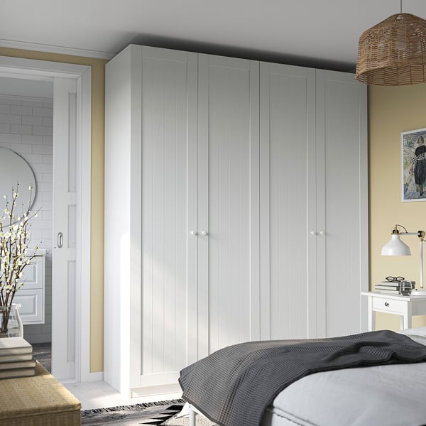 Minimalist bedroom with large white PAX wardrobe, desk, and bathroom view.