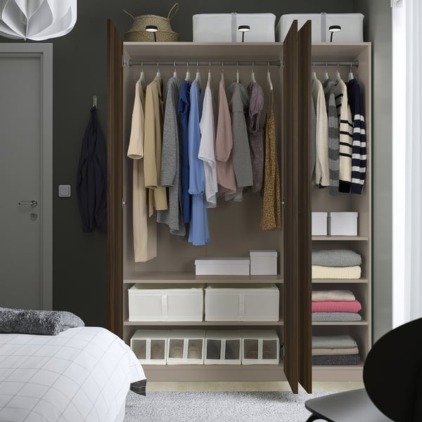 Bedroom closet with organised clothes and storage boxes. Clothes hang on rods, boxes on shelves, and a basket on top.
