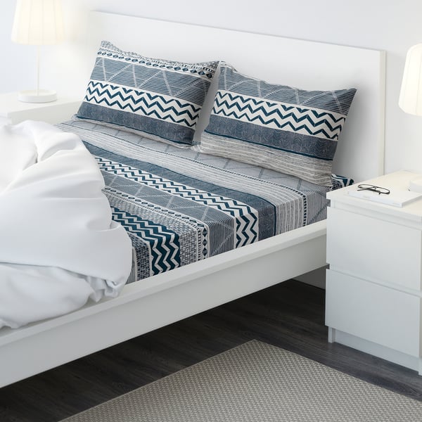 Bed with blue hosts, white linens, zigzag patterns, nightstands, lamps.