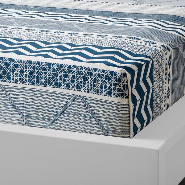 Blue and white patterned bed runner on white platform, geometric designs, cotton.