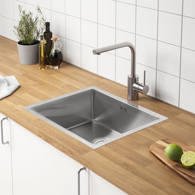 Modern kitchen sink RAFTAN in stainless steel, sleek & durable with padded corners. Sits on wooden countertop, smaller than limes.