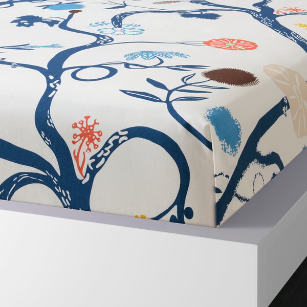 White bed with blue floral design sheet, featuring nature-themed patterns and a soft, breathable cotton blend fabric.