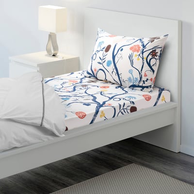 White floral bed sheet set with lamp on side table, perfect for small rooms.