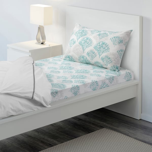 Blue leaf RÖDFIBBLA cotton bed set on white frame, neat minimalist bedroom.