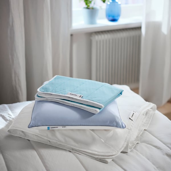 Bed with blue and grey mattress protector, ROSENVIAL brand, neatly folded on white sheets.