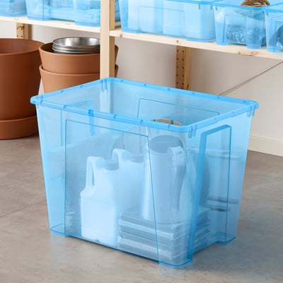 Blue plastic storage bin holding white bottles on a beige floor.