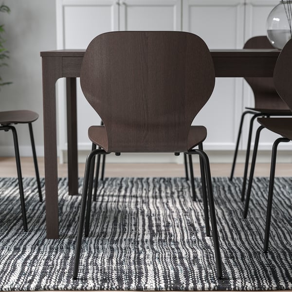 Dark wood chairs with metal legs, arranged around a table on a patterned rug. Ideal for comfort and stacking.