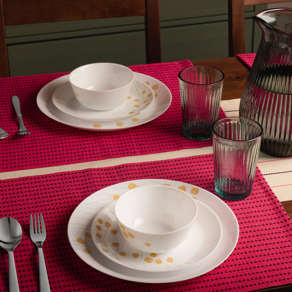 Floral dishware, red placemats, glasses, cutlery. Bowls smaller than decorated plates.