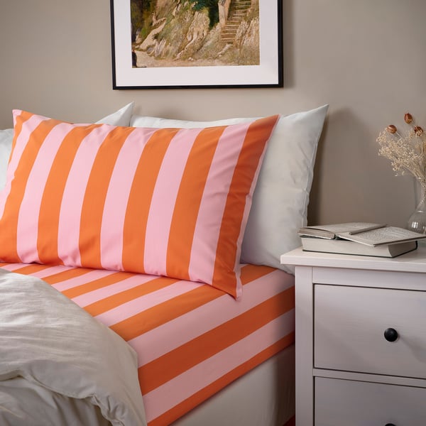 Vibrant orange & pink striped bedding in cotton and viscose, including flat and fitted sheets, plus pillowcases. Brightens neutral bedroom.