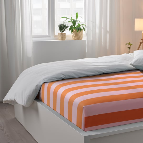 Bedroom with white bed, striped sheets, plants, curtains. Soft blend.