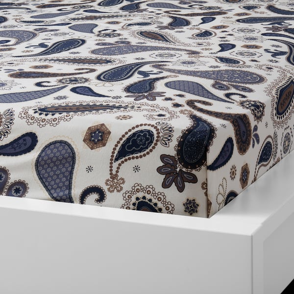 Paisley-patterned fitted sheet in muted tones on white mattress. Made of breathable cotton.