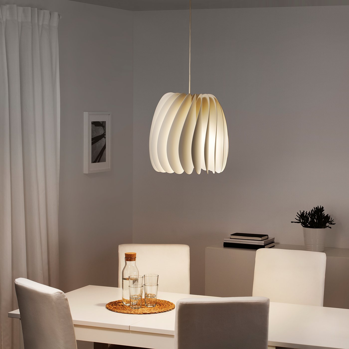 Modern dining room with pendant light, table, chairs, plant. Minimalist, cosy.