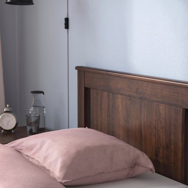 Wooden bed frame with dark finish and soft-edged headboard, adjustable for different mattress thicknesses.