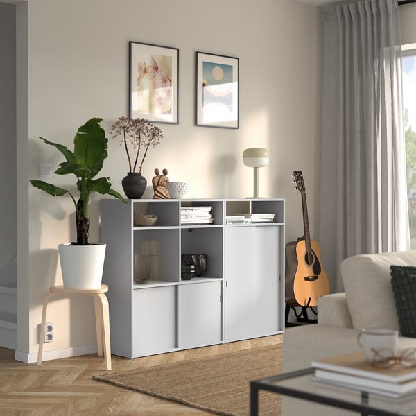 Cosy living room with SPIKSMED storage unit, books, plant, guitar, couch, and rug.