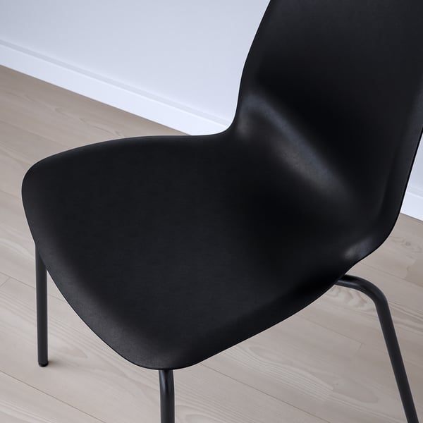 Modern black chair with sleek design on wooden floor. High-quality plastic seat and metal legs.