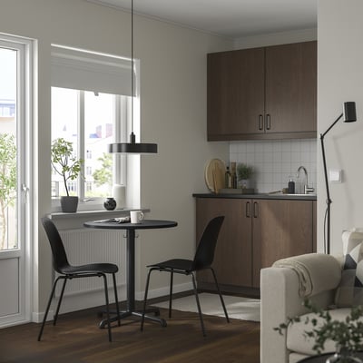 Small modern black STENSELE dining set fits neatly near window, paired with black chairs, under minimalist pendant light.