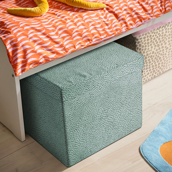 Green STJÄRNSKOTT box under bed, orange/white bedding, yellow toy, green rug.