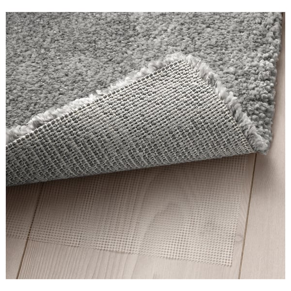 A plush, grey rug, folded to reveal its backing, with a net-like texture, ideal for sound dampening and comfort.