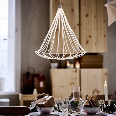Unique hanging lamp, STRÅLA, weaved white design, soft light, modern decor, above dining table, gifts and glasses, warm ambiance.