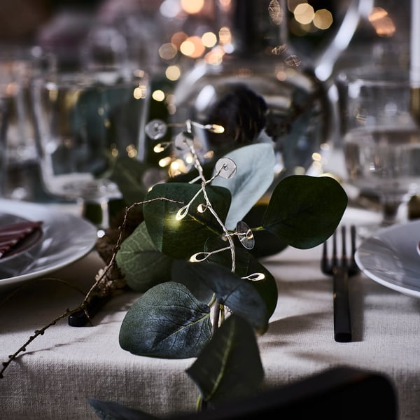Silver disc light chain decorates table with green leaves, adding warmth.