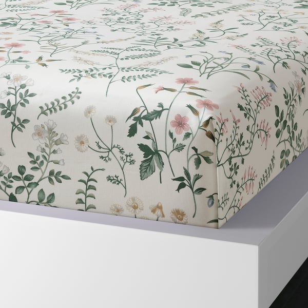 Floral-printed white bed sheet on white bed, made of soft cotton, laid flat.