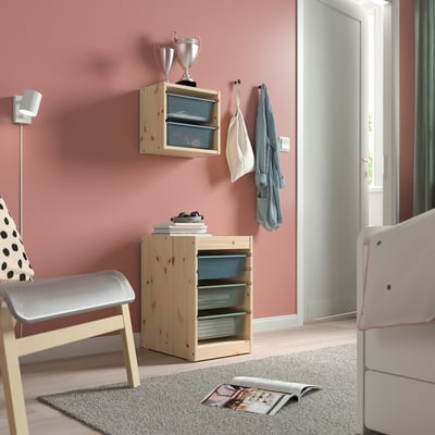 Kids room with pink walls, TROFAST shelves, books, trophies, rug, magazine.