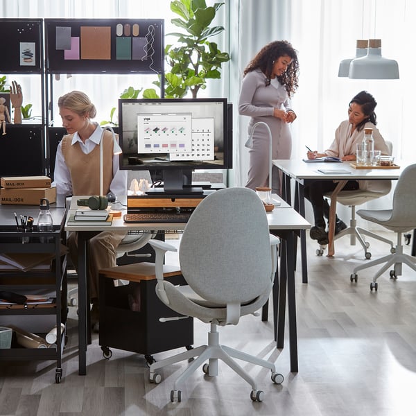 Three people working at modern desks, one using a compact TROTTENs desk.
