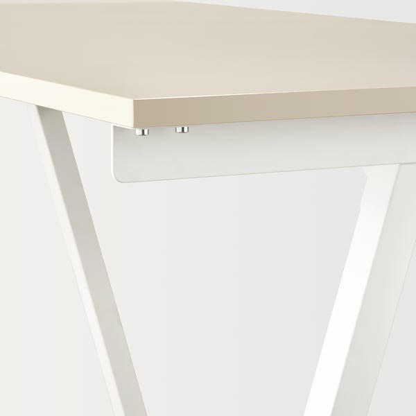 Close-up of TROTTEN desk: sleek, beige top with metallic clips, slim white legs.