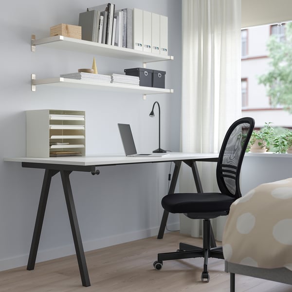 TROTTEN white desk with a-leg design, large, fits well in room, black chair, wooden floor.