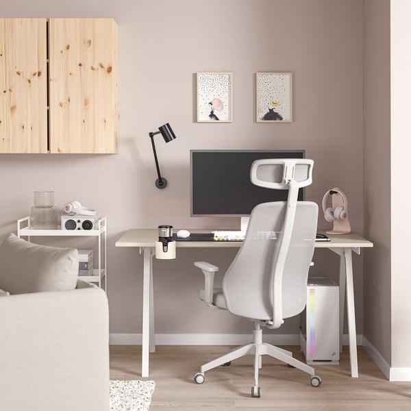 A minimalist home office with TROTTEN chair, desk, monitor, keyboard, speaker, art prints, and bookshelf with lamp.