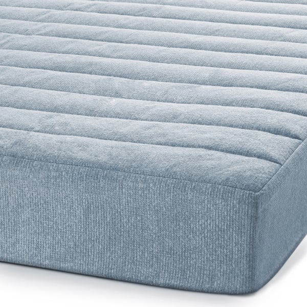 Close-up of TUNBYN mattress, showing firm, textured surface with blue fabric.