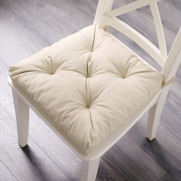 A VILDAURIKEL white chair pad with tufted design on a wooden chair. Its square, thick, and provides cushioned comfort.