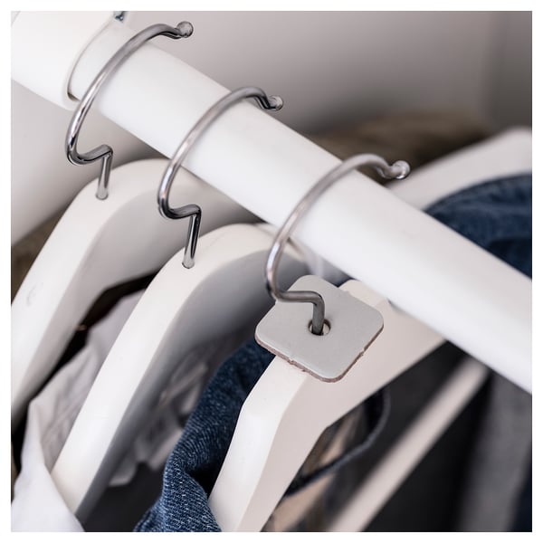 Close-up of white plastic hangers with metal hooks, holding folded clothes.