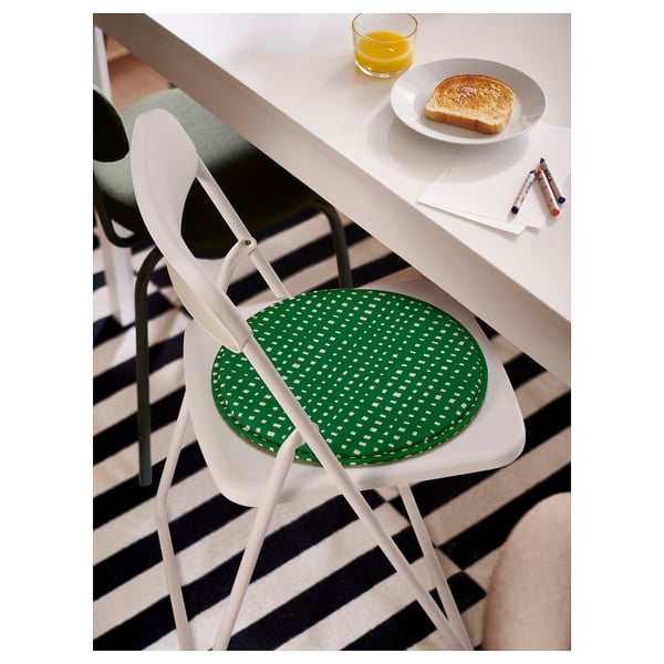 White metal chair with green cushion, non-slip base, loop. Beside table with toast, oj. Black/white rug.
