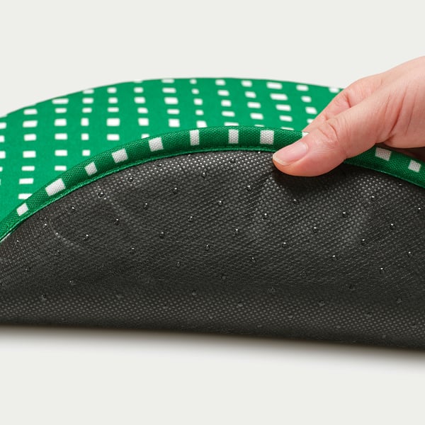 Hand lifting edge of green, white polka-dotted chair pad revealing soft, textured underside, showcasing quality materials.