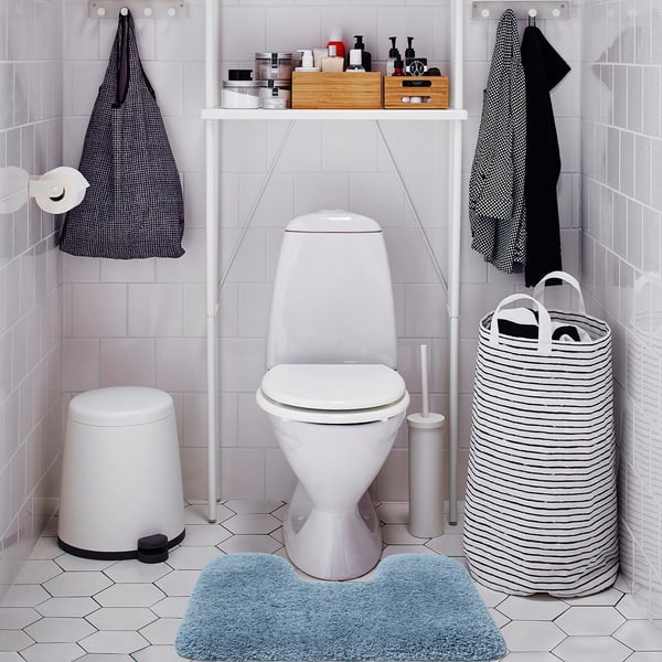 Small blue ALMTJÄRN mat, soft & absorbent, fits perfectly near toilet in clean, minimalist bathroom.