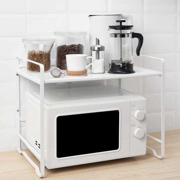 Metal rack with glasses, mugs, tea strainer, cafetière, and microwave.