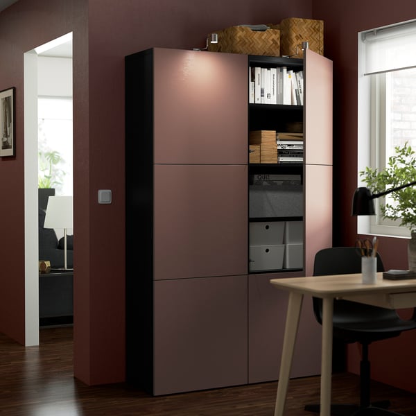 Modern home office with BESTÅ storage unit. Shelves hold binders, frames, and boxes. Integrated lighting.