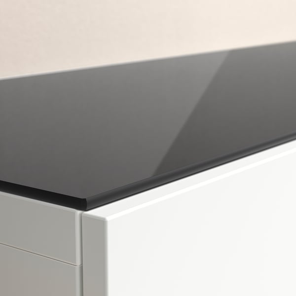 Modern, sleek glass top panel on white furniture, reflecting light.