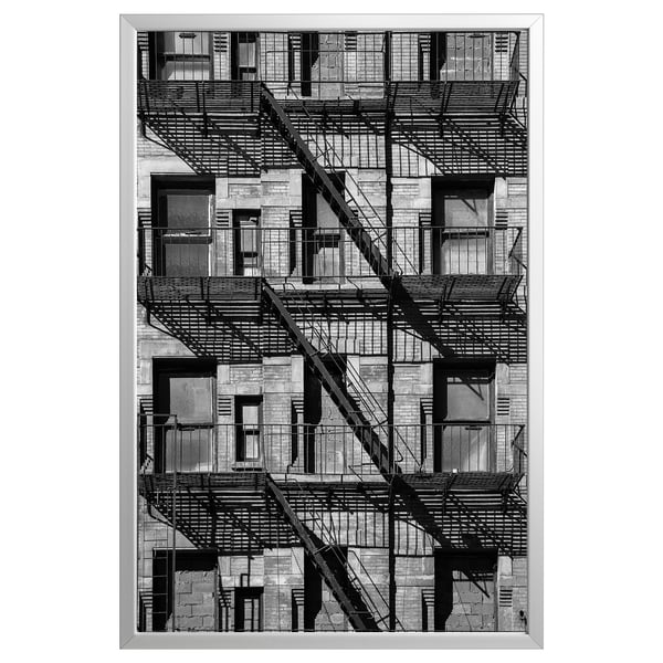 Black and white framed a multi-story building with fire escape staircases, capturing urban architecture.