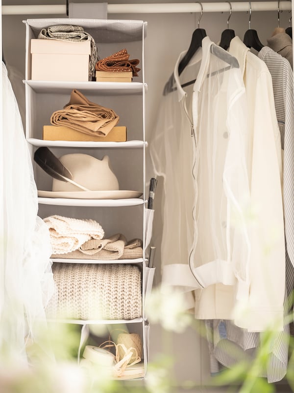 A wardrobe organiser, named BLÄDDRARE, white, made from recycled polyester, with multiple shelves and side pockets for clothes and accessories.