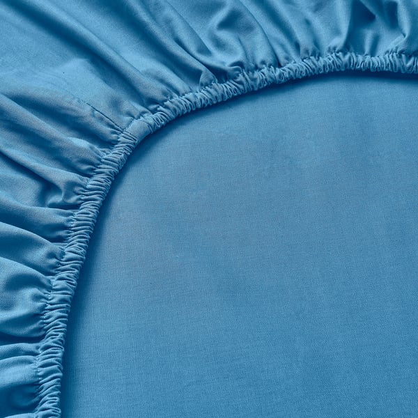 Light blue fitted sheet with elastic edges neatly laid out, showing quality cotton material.