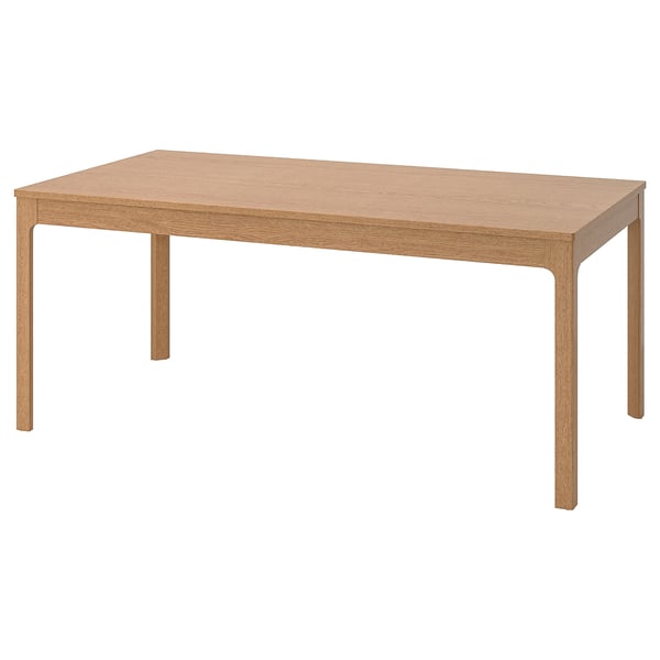 A light brown ikea EKEDALEN wooden dining table with a rectangular top and four corner legs.
