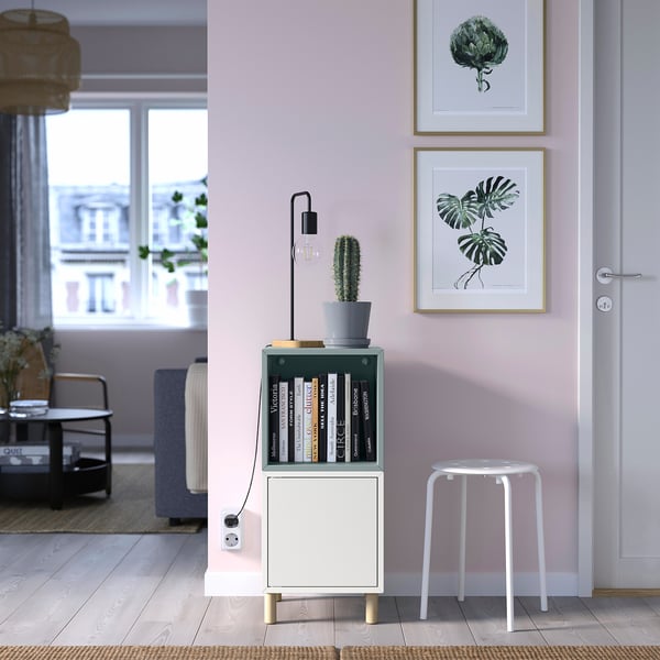 Minimalist storage unit, white, wooden legs, books, plant, stool, under window.