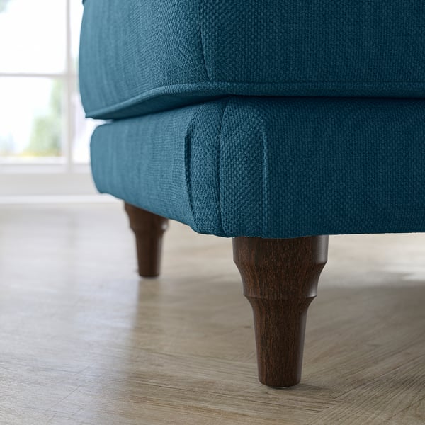 Blue upholstered footstool with wooden legs on a wooden floor.