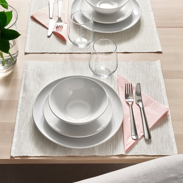 Table set with white plates, bowls, glasses, cutlery, and napkins. Simple and elegant for any occasion.