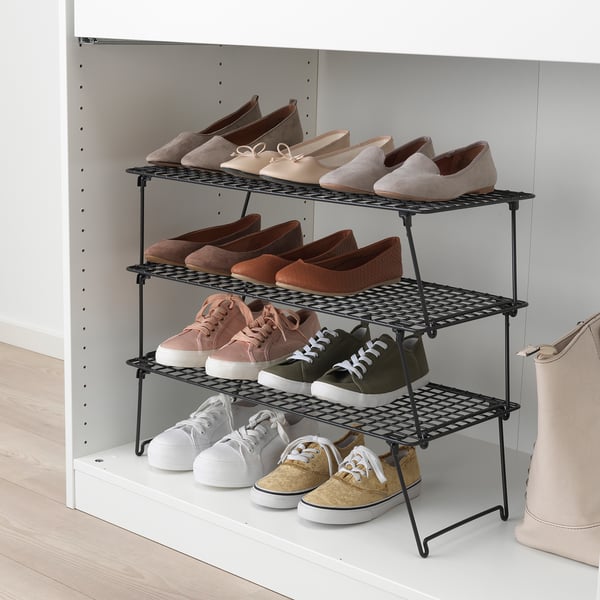 Wire shoe rack with 3 shelves in closet, holding various pairs. Black, useful for organising.