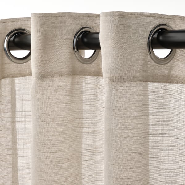 Beige sheer curtains on rod, with large eyelets for smooth hanging, allowing light while maintaining privacy.
