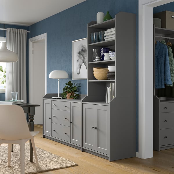 Modern living space with blue walls, grey HAUGA storage unit, drawing table, and white chair.