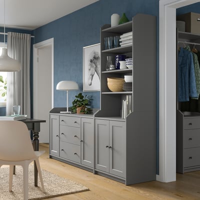 Modern living space with blue walls, grey HAUGA storage unit, drawing table, and white chair.